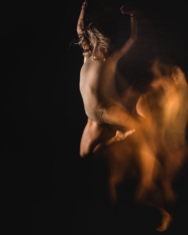 Woman performing a light cardio exercise in a modern, dark studio with pink ambient light.